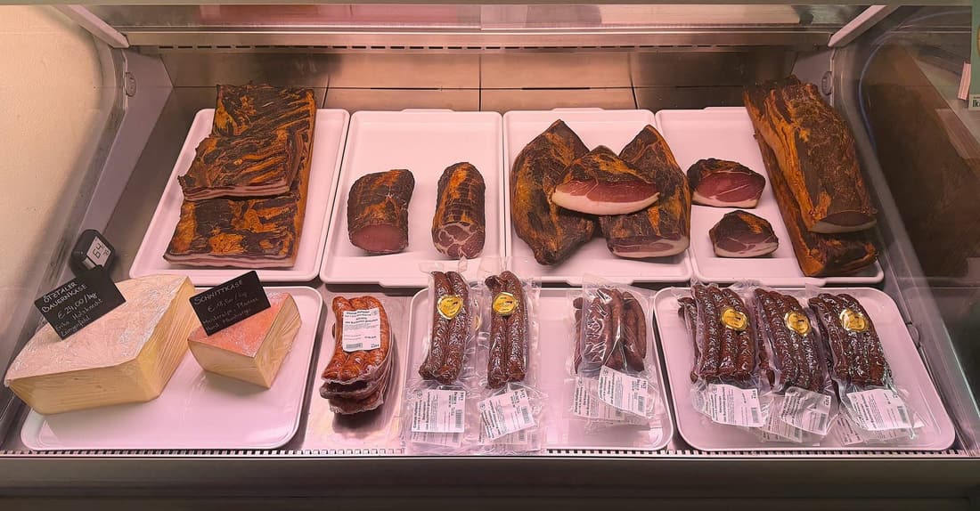 Kühlvitrine mit Speck, Käse und Würsten im Hofladen